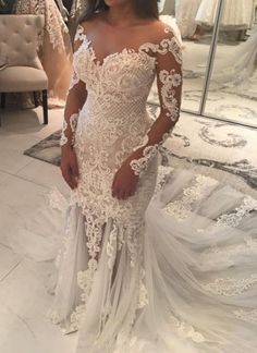 a woman in a white wedding dress standing in front of a mirror with her hands on her hips