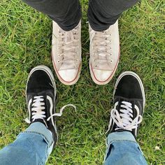 two people standing in the grass with tennis shoes on their feet and one person wearing blue jeans