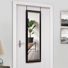 a white door with a black frame and mirror on the side wall next to a lamp