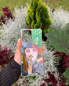 a person holding up a phone case with a painting on it