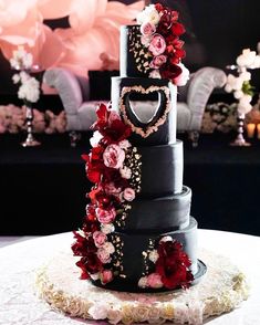 a three tiered wedding cake decorated with flowers and heart shaped decorations on a table