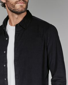 A lightweight button up crafted from a soft corduroy fabric, displaying a luxurious and handsome feel. Features fold over front placket and adjustable cuffs. Details Model is 6'1" and wears a size medium. Care: Machine wash cold on delicate cycle with similar colors. Do not use products containing bleach, oil, or alcohol. Tumble dry on low. Iron on low if needed. Dry clean for best results. Composition: 100% Cotton Casual Black Shirt With Lapel Collar, Black Shirt With Lapel Collar For Fall, Black Shirt With Button Cuffs And Relaxed Fit, Black Relaxed Fit Shirt With Button Cuffs, Black Shirt With Placket For Fall, Black Long Sleeve Shirt With Roll-up Sleeves, Black Relaxed Fit Formal Shirt, Formal Black Relaxed Fit Shirt, Black Cotton Tops With Fold Down Collar