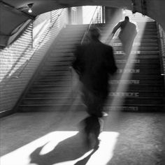 a man is walking up some stairs with his back to the camera and sunlight coming through