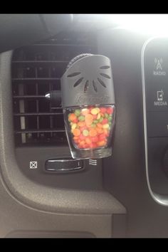 a blender filled with candy sitting on top of a car dash board next to an air vent