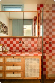 a bathroom with red and white checkered tile on the walls, vanity mirror, and shower stall