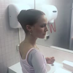 a woman standing in front of a bathroom mirror