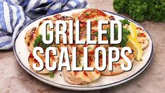 the words grilled scallops on a plate with lemon wedges and parsley