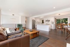 a living room filled with furniture next to a kitchen and dining room table on top of a hard wood floor