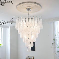 a chandelier hanging from the ceiling in a room with white walls and windows