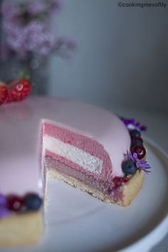 there is a pink cake with berries on it