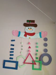 a snowman is hanging on the wall next to geometric shapes and letters that spell out numbers