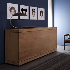 a wooden cabinet with pictures on the wall behind it