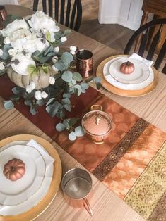 the table is set with plates, silverware and flowers