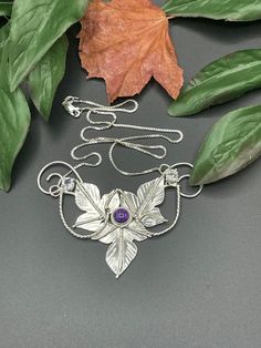 A Woodland leaves inspired necklace I've designed, entirely in sterling silver, which will feature a glowing and rich 8mm cabochon gemstone with two smaller, 4mm faceted White Topaz on either side of the main gem. This piece is approximately 3.5 inches across and I will attach a sterling silver box chain, to either end, for a total length of 18 inches when worn. If you prefer a different length, please contact me as I will adjust the chain to fit your preferences! I have offered various gemstone Hand Forged Silver Necklaces In Nature-inspired Style, Hand Forged Silver Nature-inspired Necklace, Hand-forged Silver Nature-inspired Necklace, Silver Mystical Necklace With Cabochon, Silver Amethyst Cabochon Necklace, Silver Amethyst Necklace With Cabochon, Nature-inspired Silver Amethyst Jewelry, Mystical Hand Forged Sterling Silver Necklaces, Hand Forged Mystical Sterling Silver Necklaces