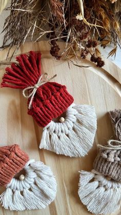 three knitted ornaments are sitting on a wooden table next to dried twigs and pine cones