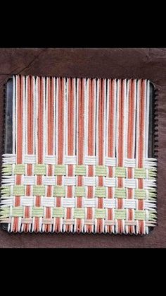 an orange and white place mat on top of a wooden table next to a knife holder