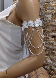 a mannequin wearing a white dress with flowers and chains on it's arm