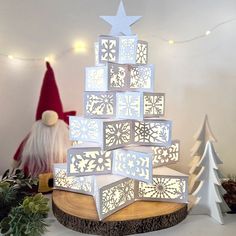 a christmas tree made out of cut outs and snowflakes is displayed on a table