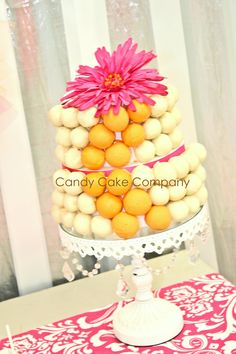 a three tiered cake decorated with lemons and a pink flower sits on a table