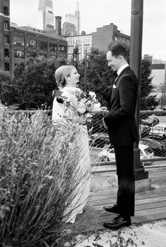 a man and woman standing next to each other on a wooden platform in front of tall buildings