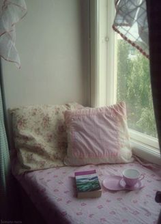 a window sill with a book, cup and saucer sitting on top of it