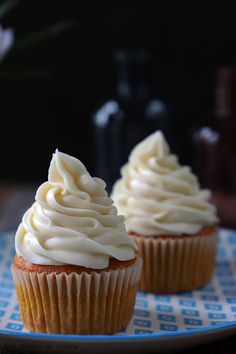 two cupcakes with white frosting on a blue plate