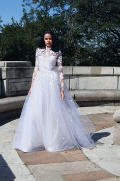 a woman in a wedding dress standing on a stone walkway