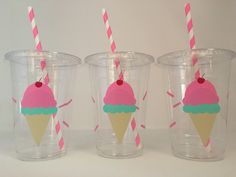 three plastic cups with pink and blue ice cream on them, one has two straws in it