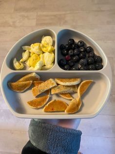 a person holding a plate with fruit and vegetables on it