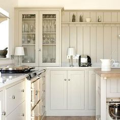 a kitchen with white cabinets and wood flooring is pictured in this image, there are dishes on the counter