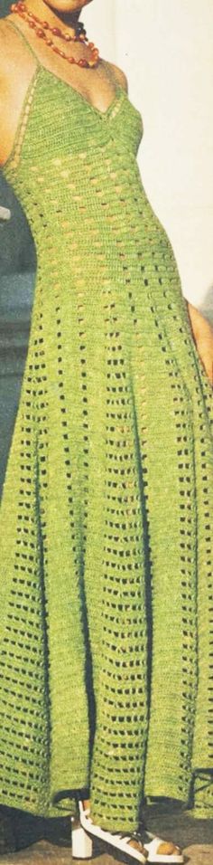 a woman in a green crocheted dress is on a skateboard and looks off to the side