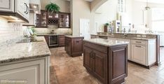 a large kitchen with marble counter tops and wooden cabinets