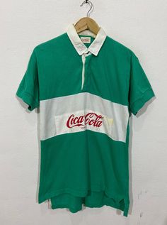 "*ITEM: Vintage Coca Cola Polo Rugby Shirt Medium 1990's Carbonated Usa Drink Coke Soft Drink Green Stripes Polo Shirt Size M *ITEM DETAILS: 👇🏻 Please be aware that all vintage items will usually show a few signs of wear or fading due to age, but anything visible such as stains or holes, and serious flaws have been photographed.For any further information on this item please contact us and we will be happy to help. *SIZE: MEDIUM *ACTUAL SIZE MEASUREMENT: 👇🏻 *PIT TO PIT(WIDTH):20\"INCHES *LEN Retro Collared T-shirt For Streetwear, Retro Green Collared T-shirt, 90s Cotton Collared Tops, Vintage Green Collared Top, Vintage Green Shirt For Streetwear, Vintage Green Streetwear Shirt, Vintage Green Collared T-shirt, Vintage Green Cotton Tops, Usa Drinks