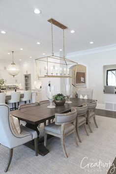 a dining room table with chairs and a chandelier hanging from the ceiling above it