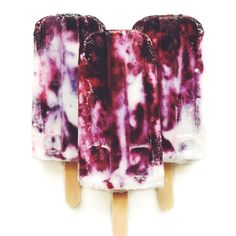 three popsicles with blueberries and raspberry sauce on them