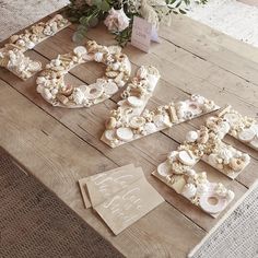 the table is covered with letters made out of shells and seashells, along with a bouquet of flowers