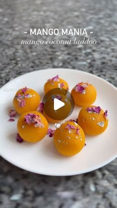 some oranges are sitting on a white plate and have been decorated with pink flowers