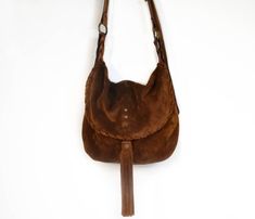 Crossbody bag made with soft cognac suede and stronger cognac leather. This bag has a soft structure and a very strong shoulder strap made with hand-dyed leather. The bag is a medium size messenger with a slightly rounded shape and a soft structure, the flap is embellished by a suede seam and a beautiful suede tassel. The shoulder strap width is 0.8 inch. The shoulder bag is adjustable with a beautiful buckle. The bag is unlined. Features : - Cognac suede, - Cognac leather, - Brass colored metal Brown Suede Crossbody Shoulder Bag, Brown Suede-lined Crossbody Shoulder Bag, Strong Shoulders, Suede Tassel, Leather Bag Women, Leather Bags Handmade, Green Suede, Leather Hobo, Brass Color