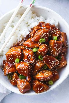 a bowl filled with chicken and rice next to chopsticks