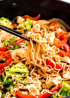 noodles, broccoli and peppers are being stirred with chopsticks in a skillet