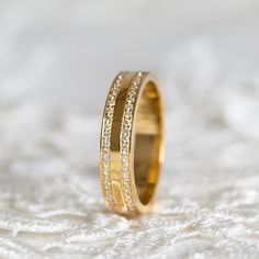 a wedding ring with two rows of diamonds on top of white lace fabric, close up