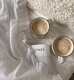 two mugs of coffee sitting on top of a white blanket