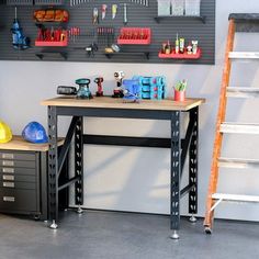 a workbench with tools on it in front of a wall mounted pegboard