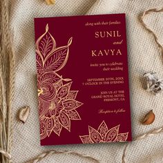 a red and gold wedding card on top of some burlocked linens