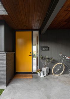 a bicycle is parked in front of a yellow door on the side of a house