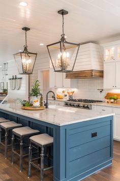 a kitchen island with stools in front of it and lights hanging from the ceiling