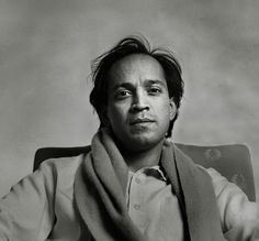 a black and white photo of a man with a scarf around his neck sitting in a chair