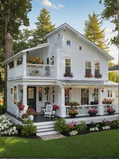 a white house with lots of flowers on the porch