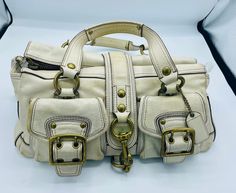 This amazing Rare Legacy Limited Coach Ivory handbag is super fantastic! Heavy brass hardware and buckles make this a true classic. One of Teri Hatches favorite bags.  Was 1495.00 new $350.00 Coach Purses Coach, White Satchel With Metal Hardware For Travel, Luxury Satchel Bag With Hardware, Designer Beige Satchel With Metal Hardware, Luxury White Bags With Brass Hardware, White Luxury Bags With Brass Hardware, White Leather Bags With Brass Hardware, Ivory Handbag, Accessorize Bags