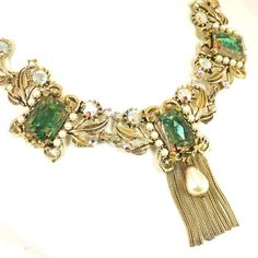 This is part of Chairish’s Costume Jewelry assortment.  Offered here is an Amerique Baroque-style gold-plated necklace and matching clip-back earrings from the 1950s. The design exemplifies classic Baroque characteristics, include flowing lines, floral motifs, and an obsession with symmetry. The central portion is comprised of three panels linked together, each in a mirror-image motif of curling ribbons and leaves. Each segment is centered with a large bi-color watermelon glass stone, flanked by Vintage Green Clip-on Jewelry, Vintage Green Evening Jewelry, Retro Green Jewelry For Evening, Vintage Jeweled Necklaces For Vintage Events, Antique Clip-on Jewelry For Parties, Vintage Necklace For Vintage Events, Ornate Baroque Jewelry For Party, Vintage Green Necklace For Evening, Vintage Green Necklaces For Evening